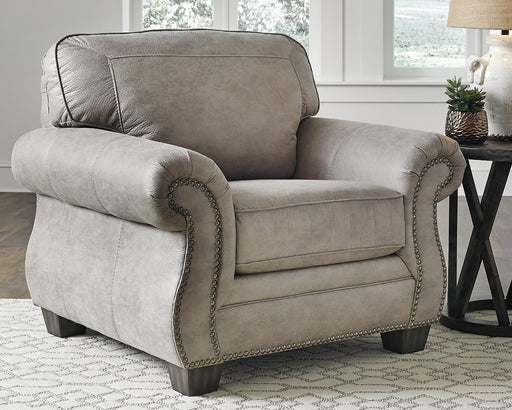 Olsberg chair in a cozy living room, featuring steel gray suede-like upholstery, nailhead trim, and elegant roll arm design.