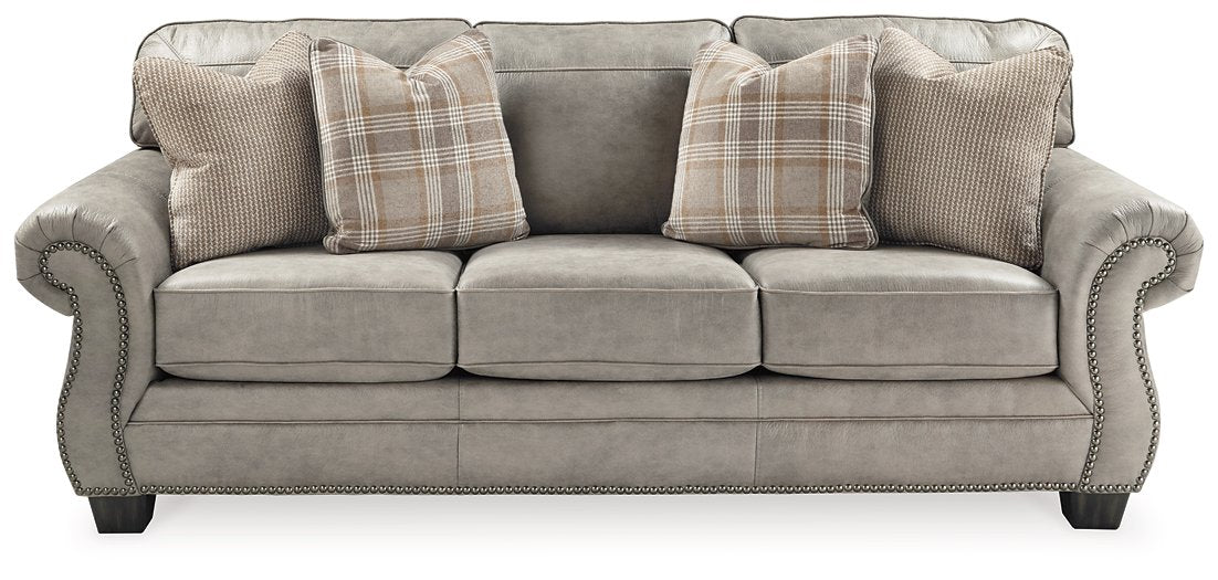 Front view of the Olsberg Sofa with steel gray upholstery, nailhead trim, and plaid accent pillows. Elegant and cozy design.